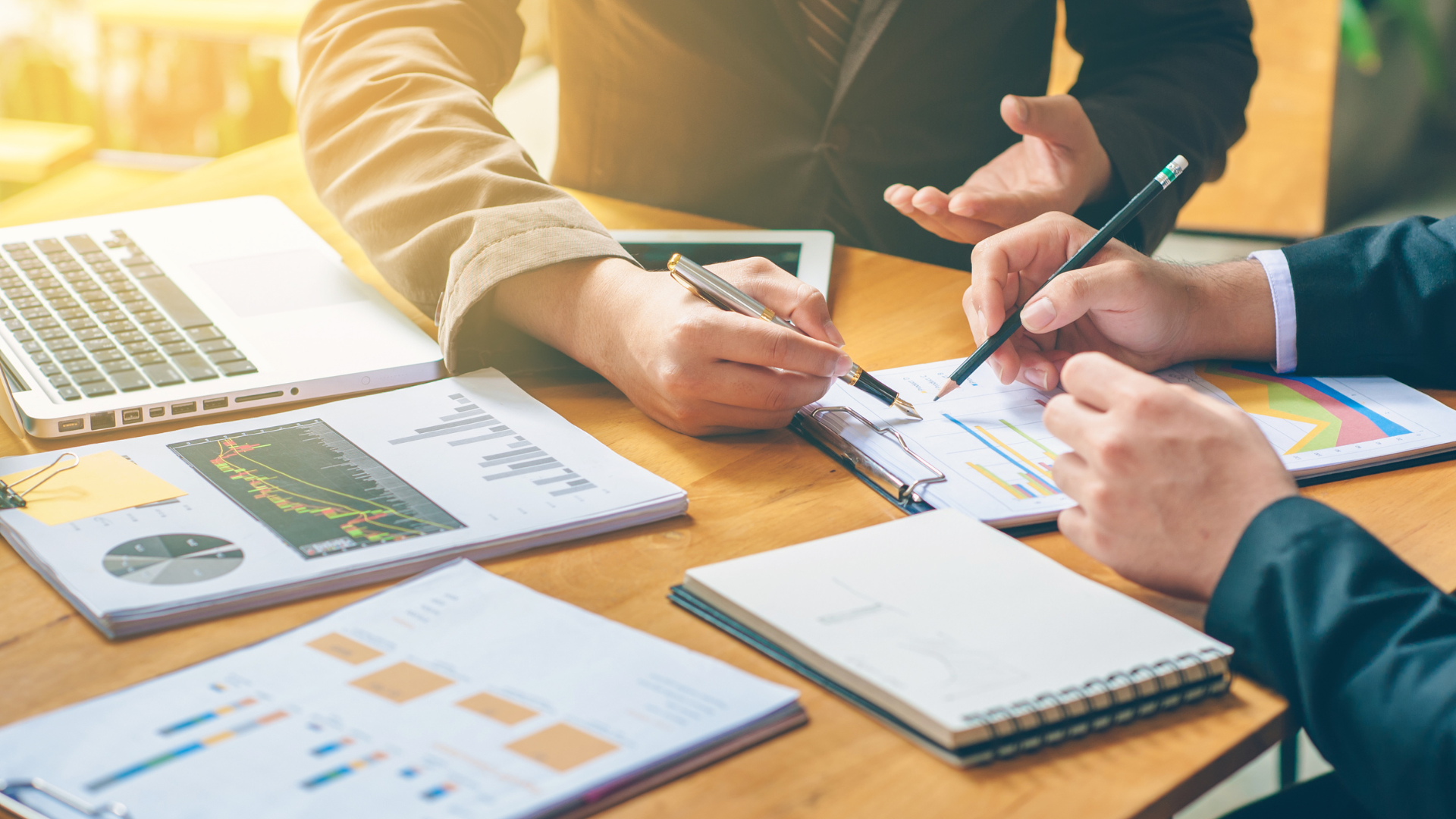 Personas analizando informes y gráficos en una mesa de trabajo, simbolizando planeación estratégica y toma de decisiones